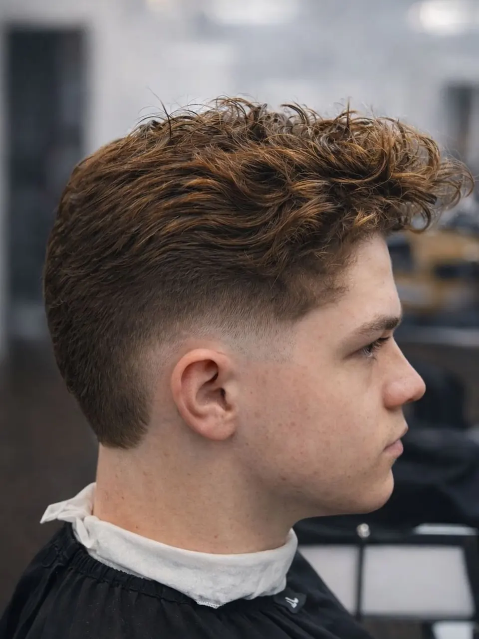Textured curly top with a burst fade around the ear
