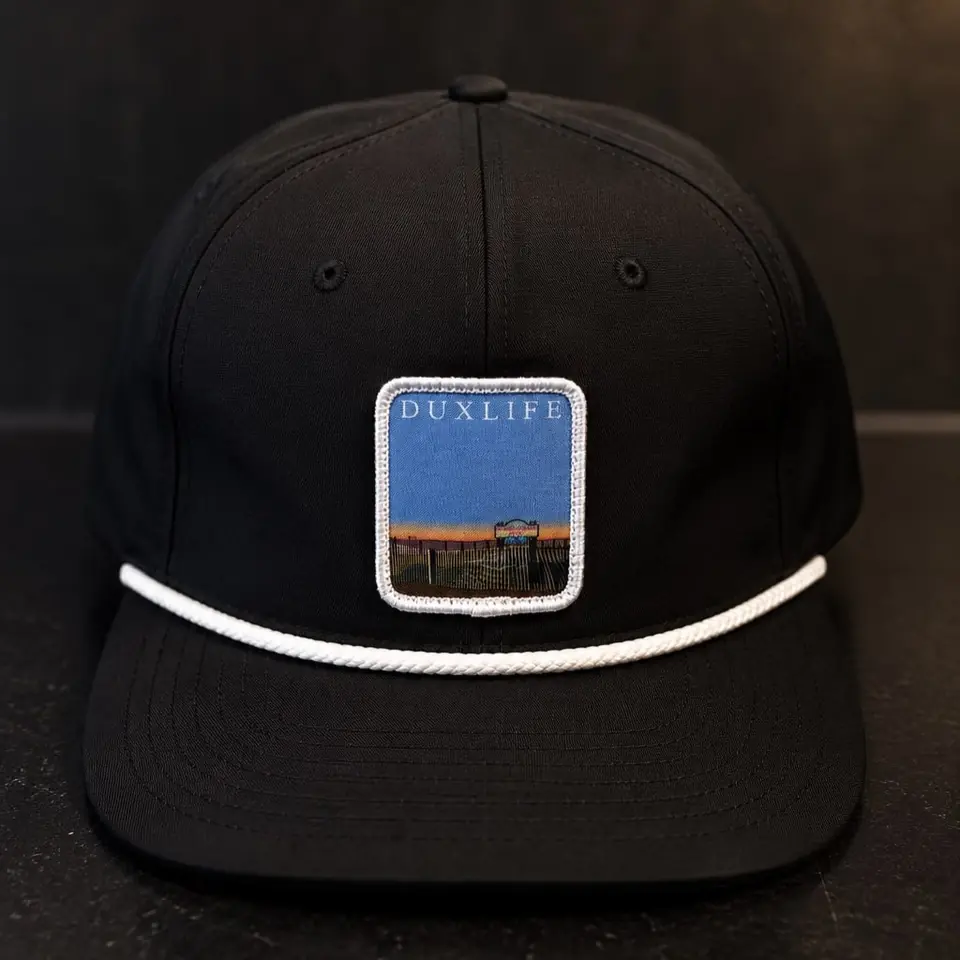 A black Duxlife hat with a sunset patch