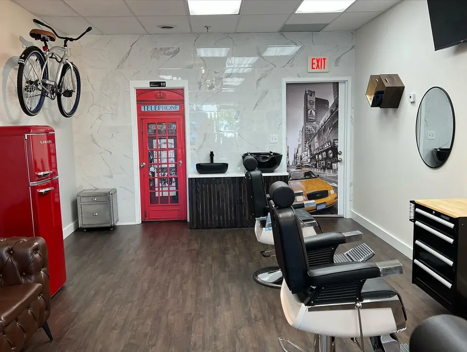 Inside the shop: black barber chairs, round mirrors, a red phone-box door and a bicycle on the wall