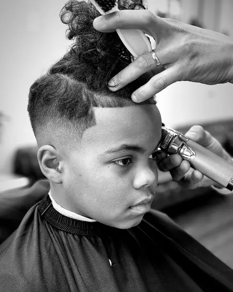 Black and white photo of a boy's curly top being shaped