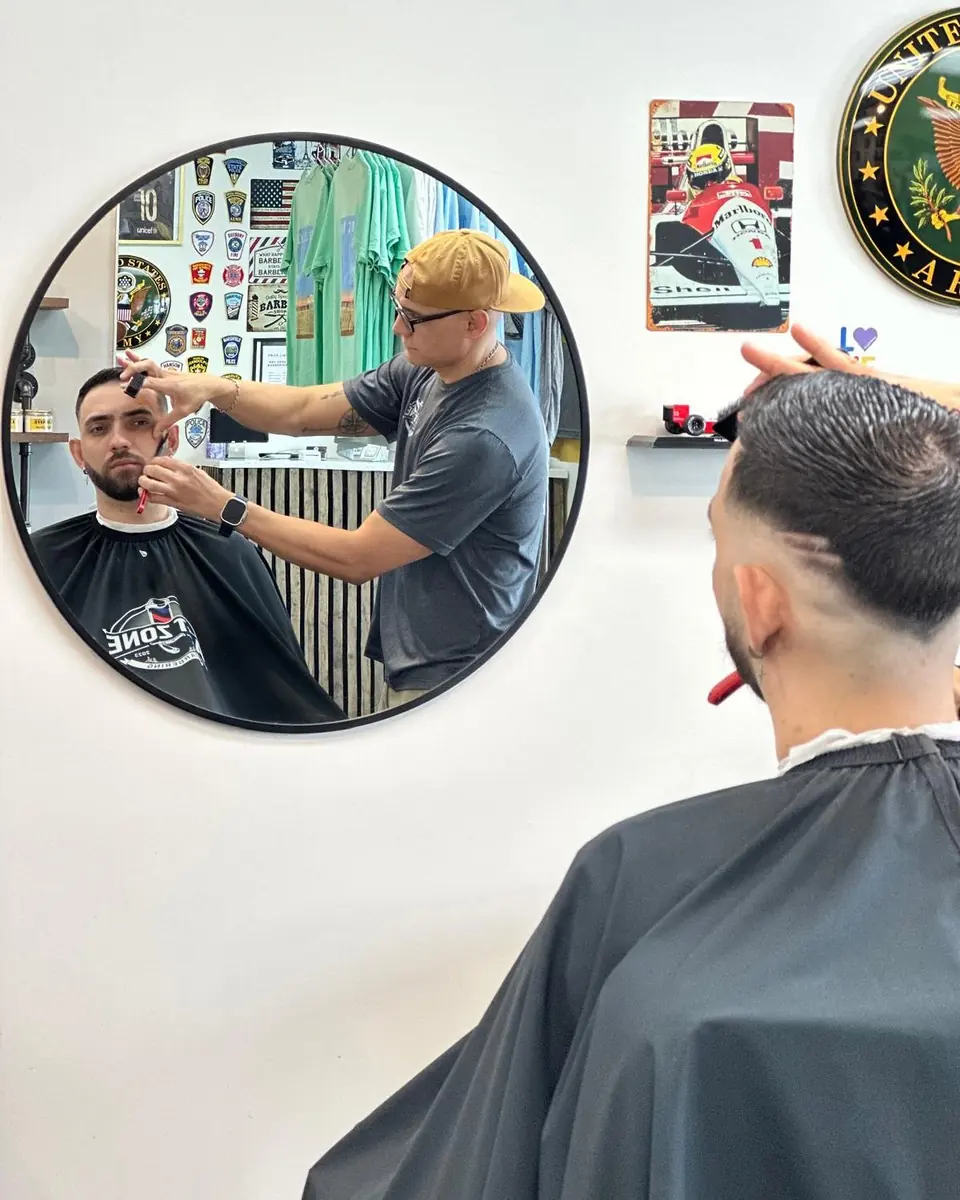 Luke cutting a client, reflected in one of the shop's round mirrors
