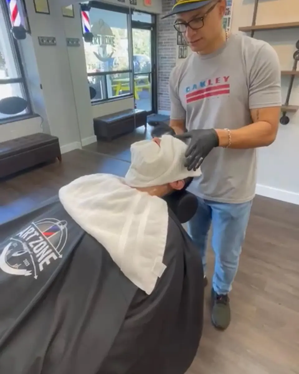 A client reclined under a hot towel before the shave