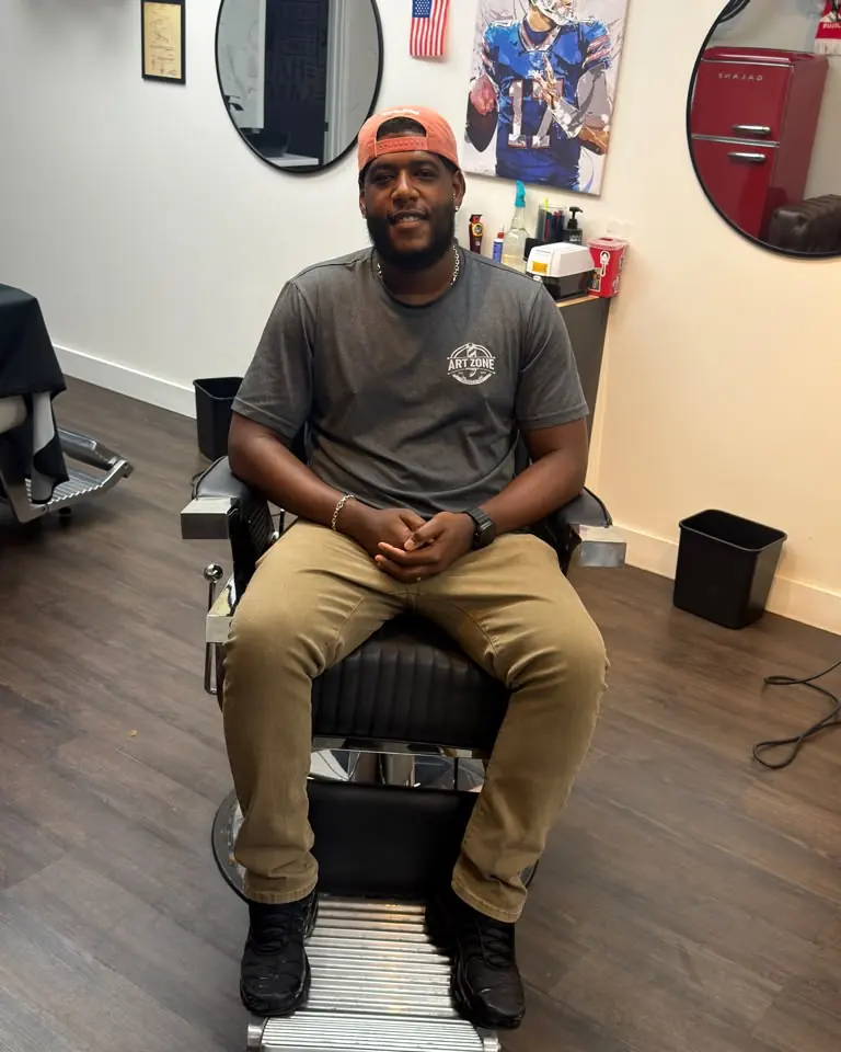 Paulo, barber at Art Zone, sitting in a barber chair