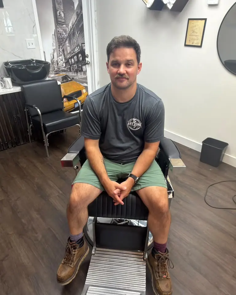 Tim, barber at Art Zone, sitting in a barber chair